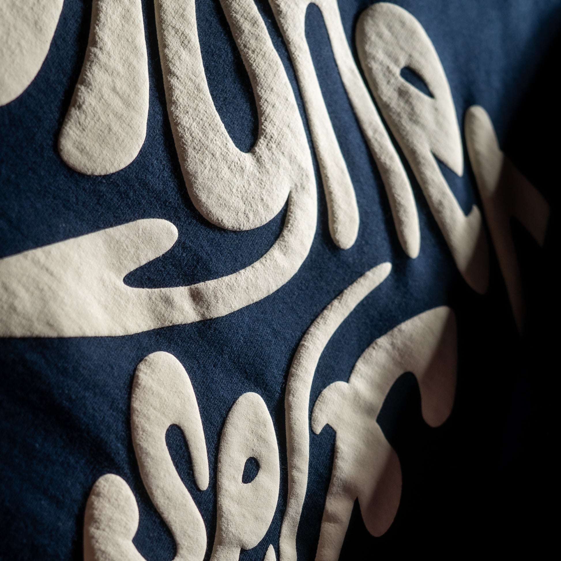 Close-up of a 3d Puff Print with embossed text on a dark background