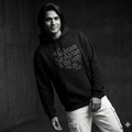 Person wearing a black hoodie with text against a dark background
