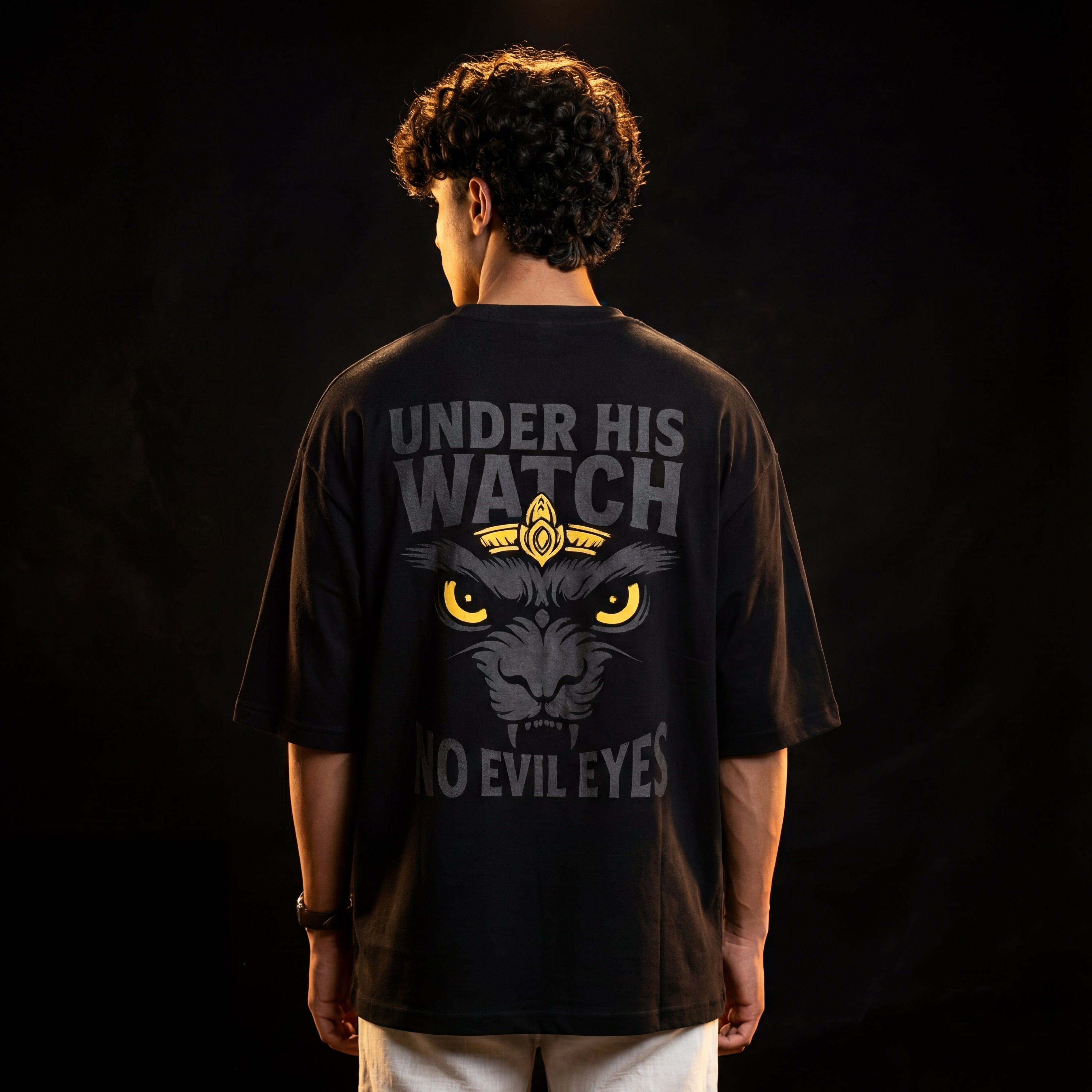 Person wearing a black t-shirt with a graphic design and text on the back against a dark background