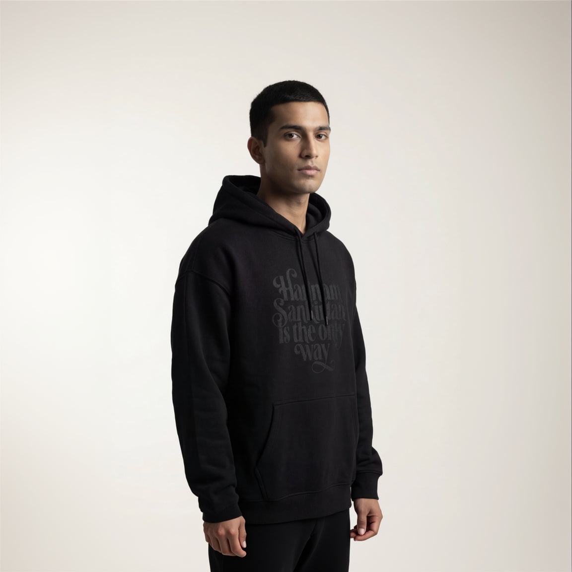 Person wearing a black hoodie with text on a plain background