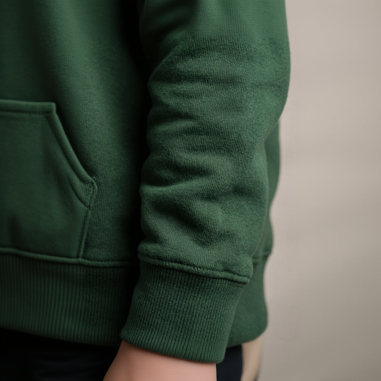 Close-up of a green sweater sleeve on a neutral background